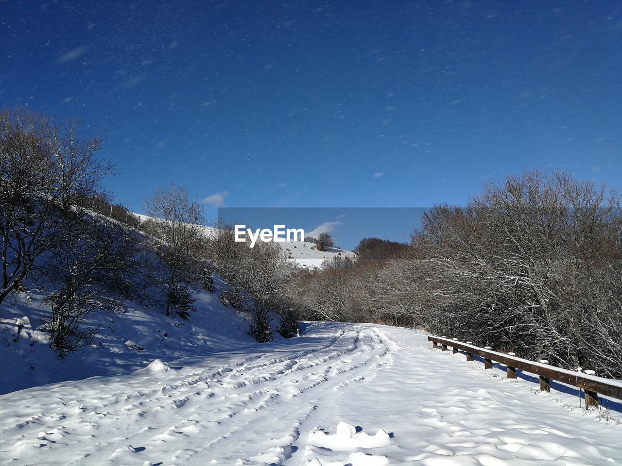 Snow covered landscape against clear blue sky