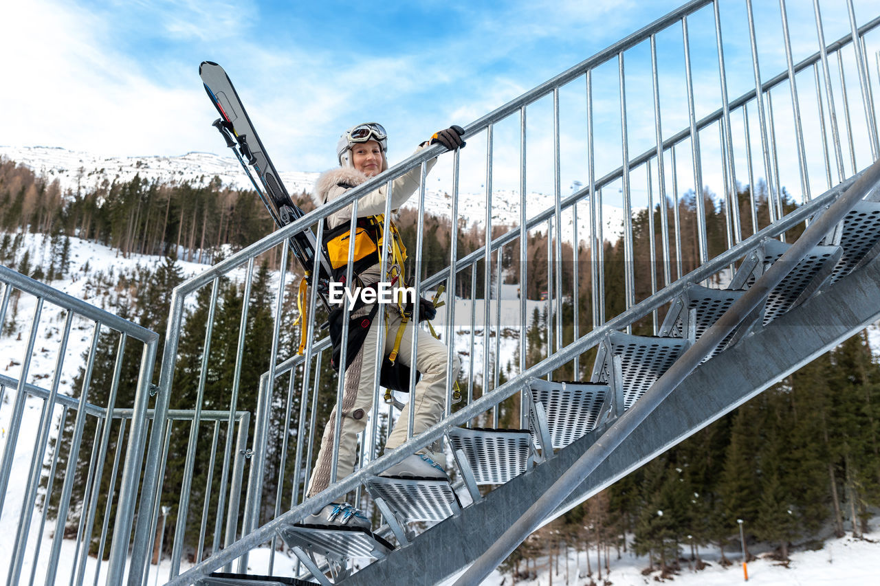 Low angle view of man on snow covered railing