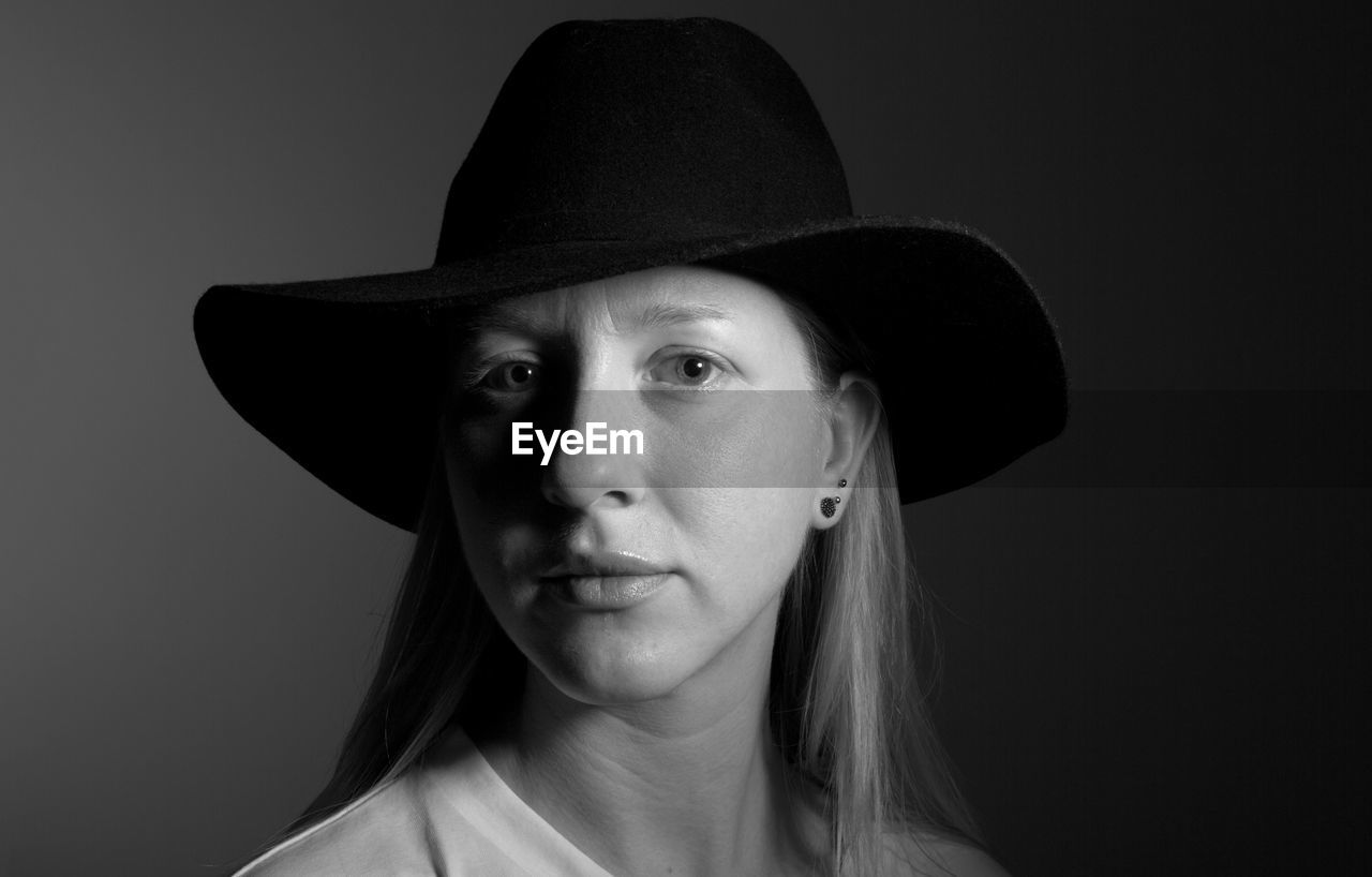 Portrait of woman wearing hat against black background