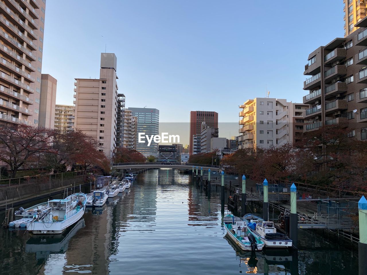 Boats in canal amidst buildings against clear sky