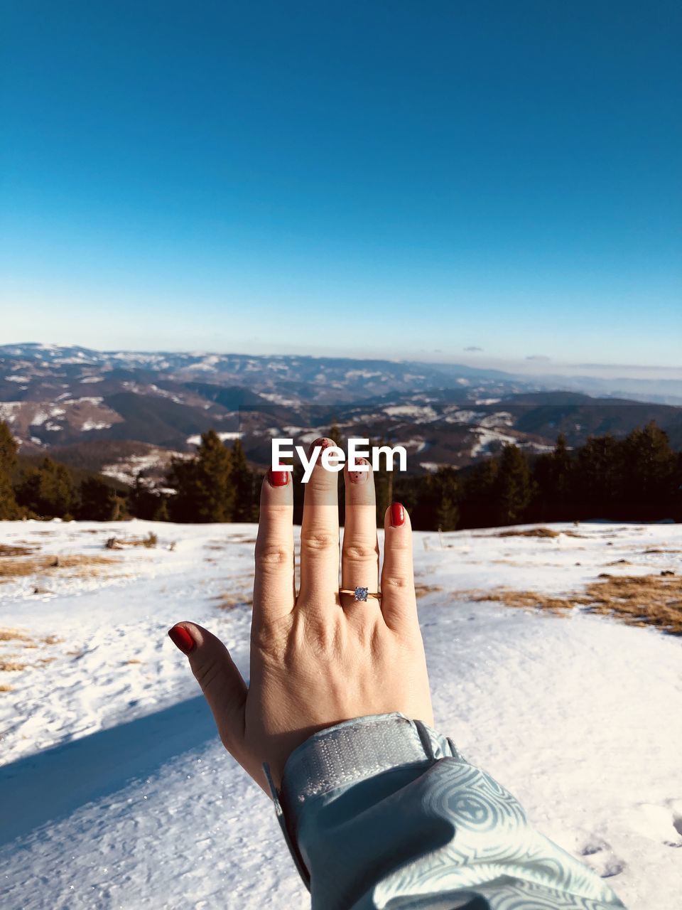 Midsection of person against blue sky during winter