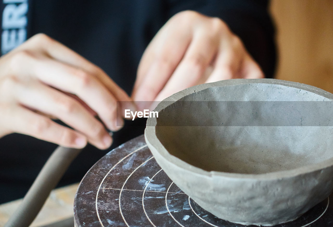 Close-up of person making clay bowl