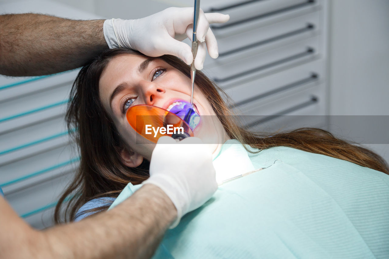 Cropped hands of male dentist examining female patient in clinic