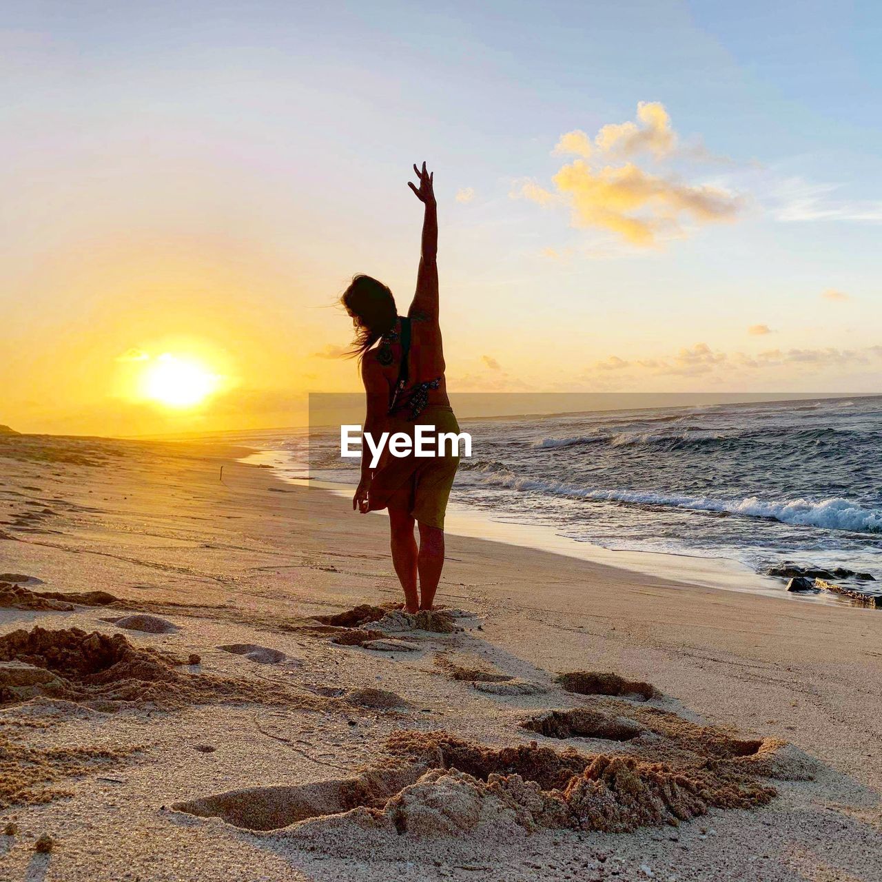 MAN STANDING ON BEACH DURING SUNSET