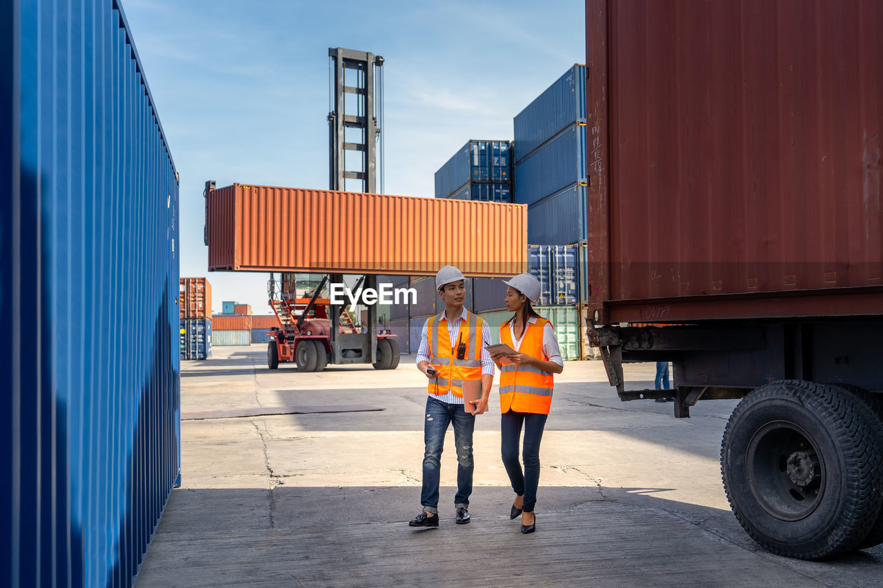 Engineers are overseeing the transportation of cargo with containers inside the warehouse.