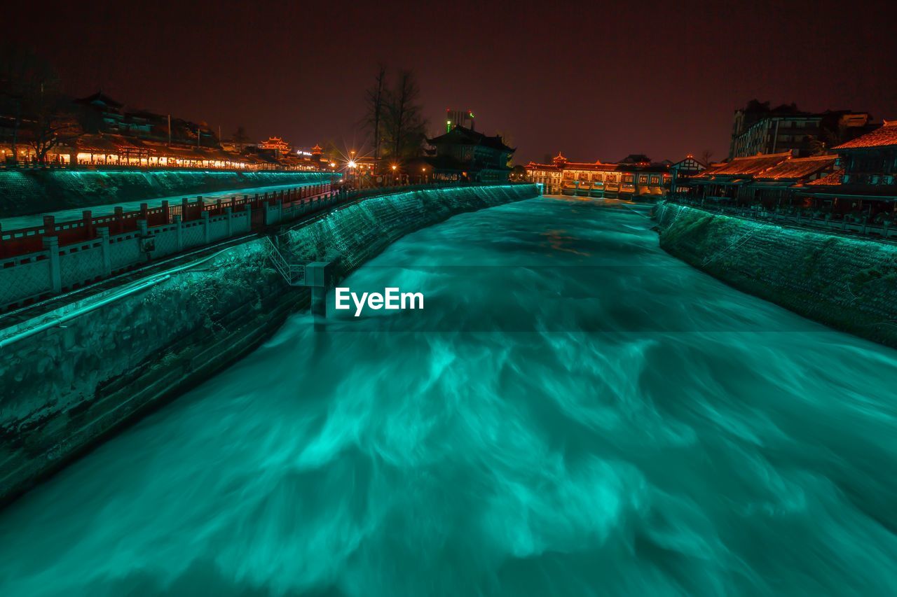 Swimming pool by sea against sky at night