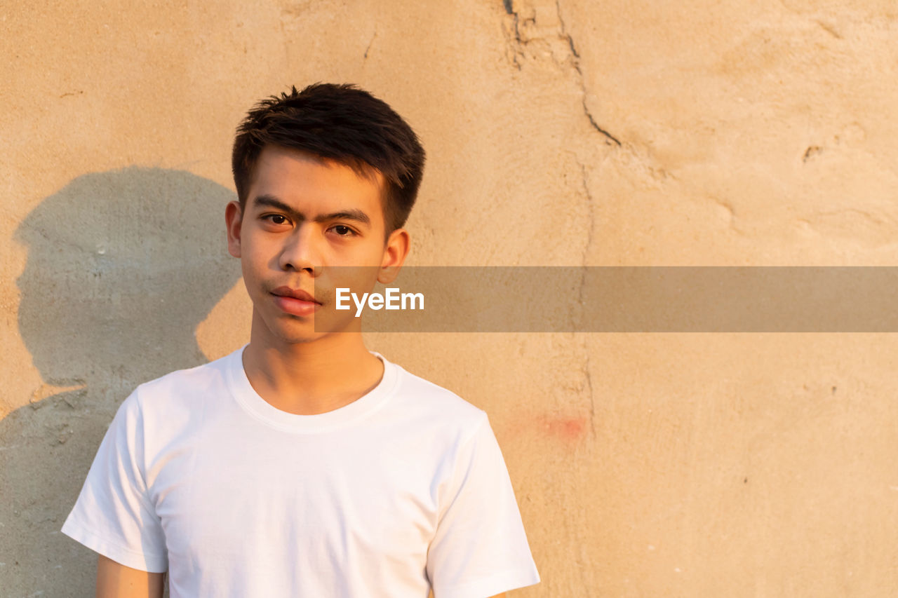 Portrait of young man standing against wall