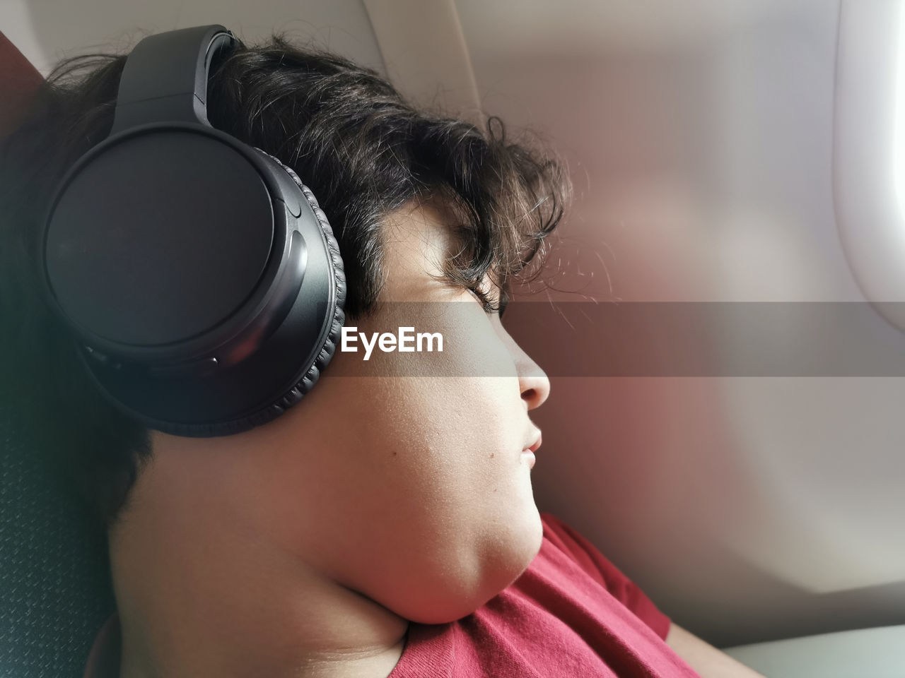 Boy relaxing listening to music on headphone during flight.