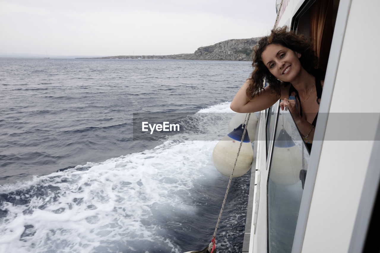 Portrait of young woman looking though ferry window