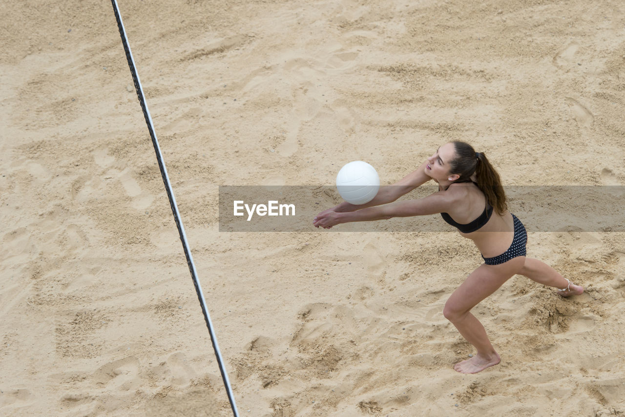 Girl playing with ball on sand at beach