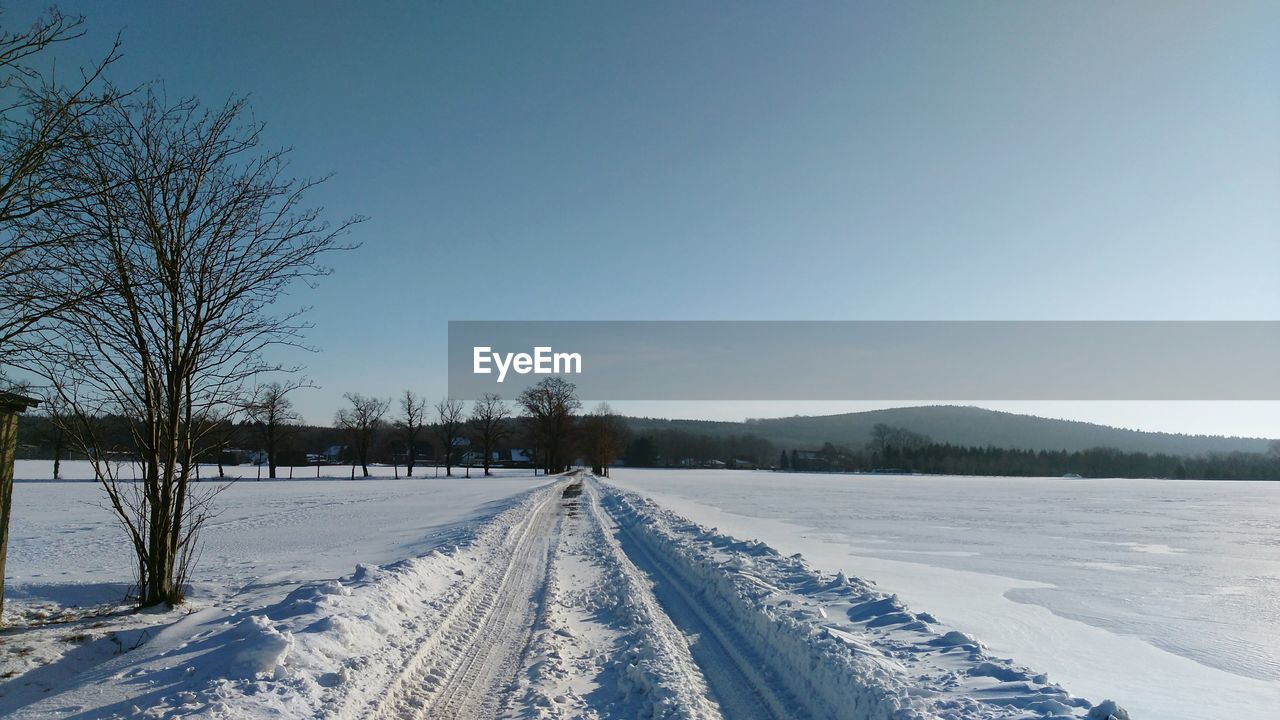 Snow covered field against clear sky