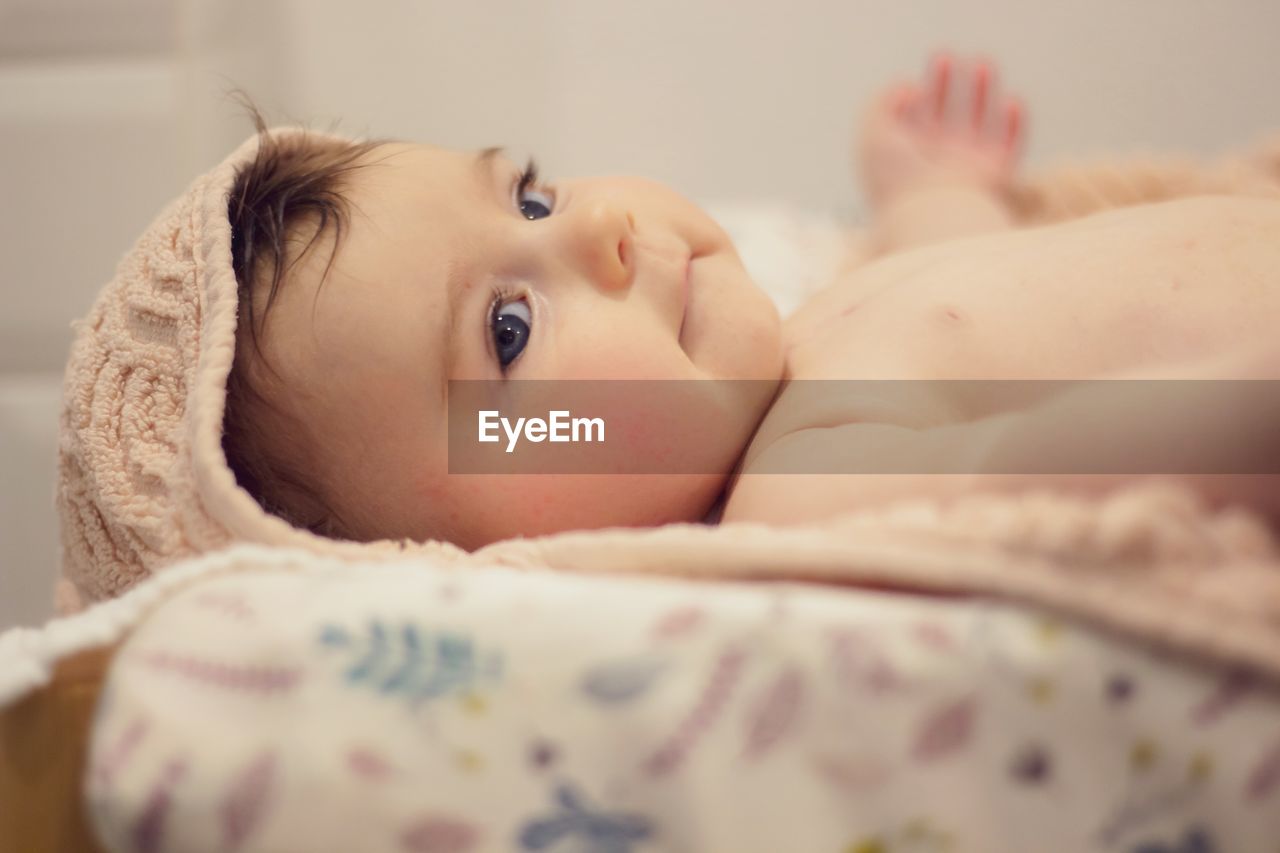 Close-up of cute baby girl on bed at home