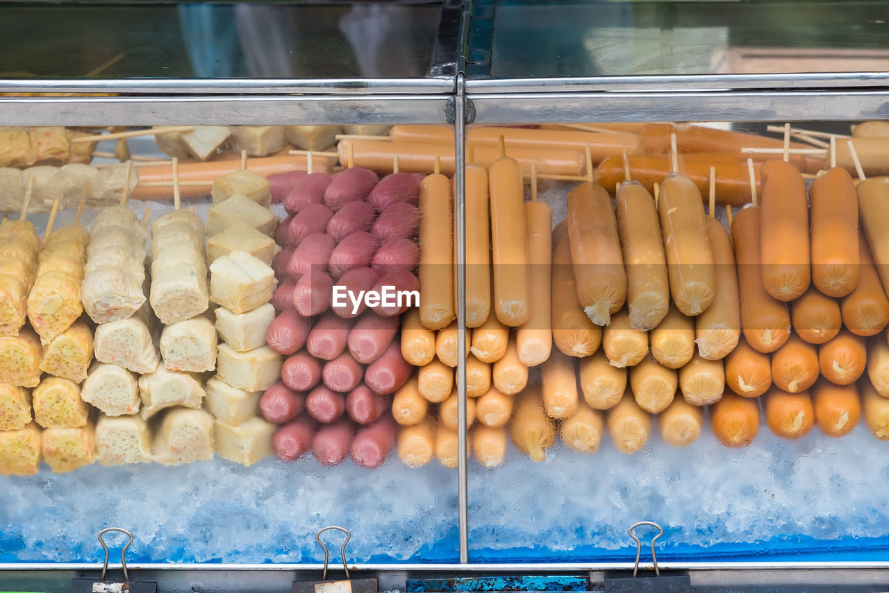 Raw sausages and meat arranged in display cabinet for sale at market