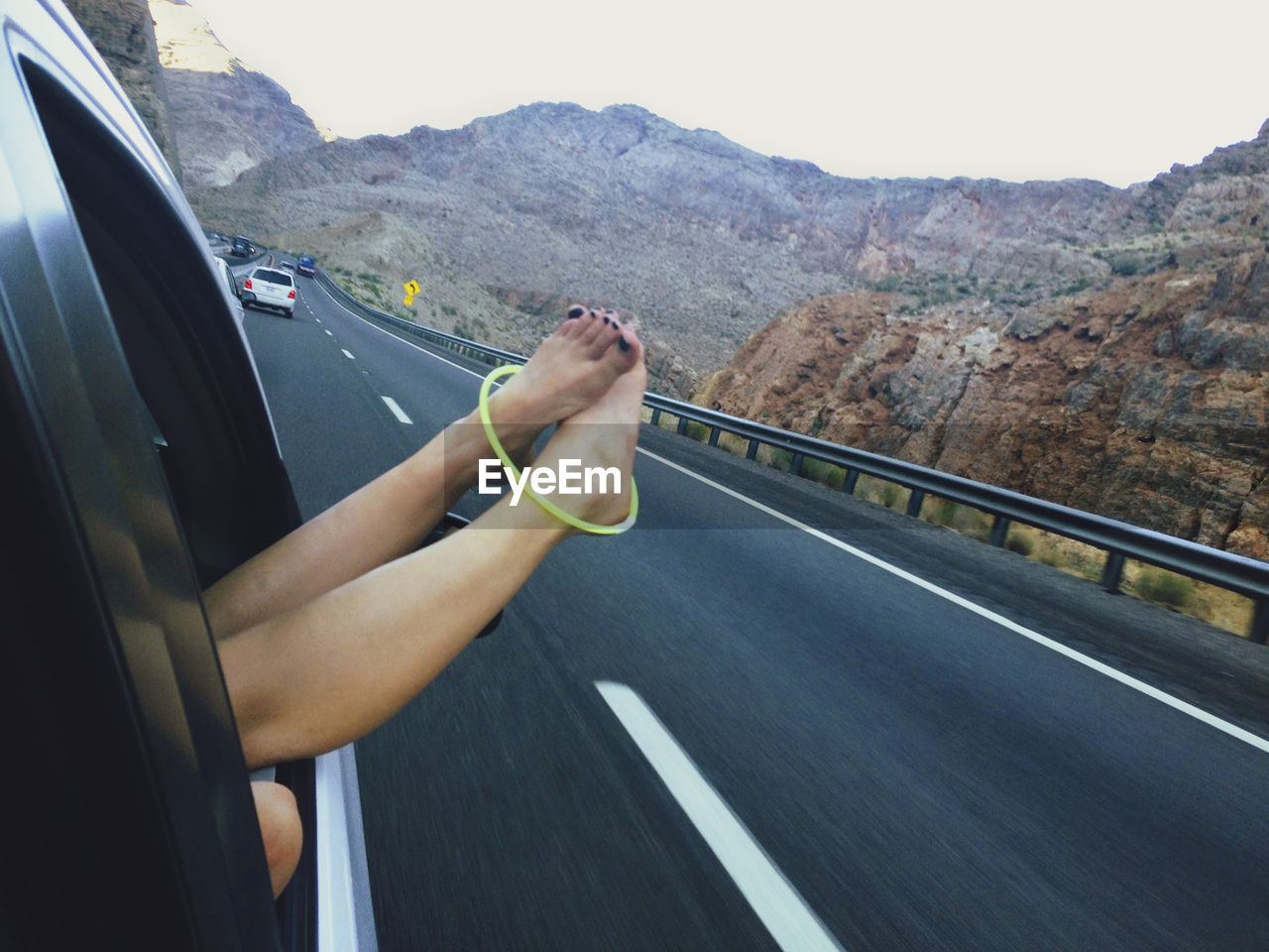 Low section of woman with feet outside car window