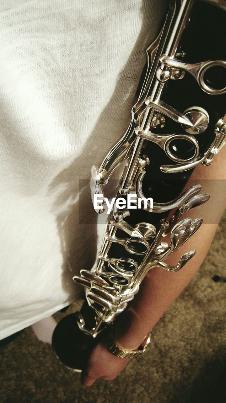 Midsection of man holding clarinet