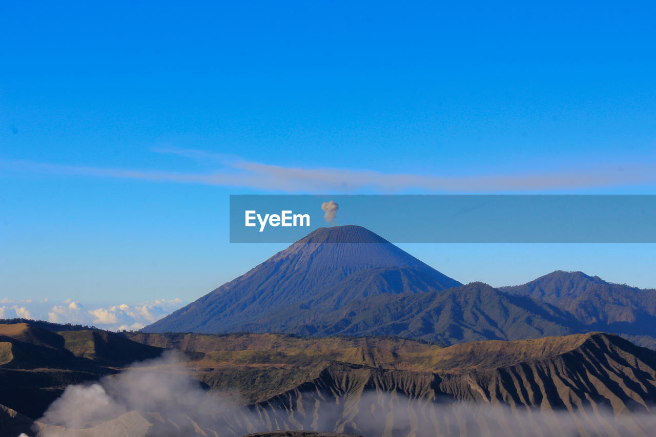 Scenic view of volcano against blue sky