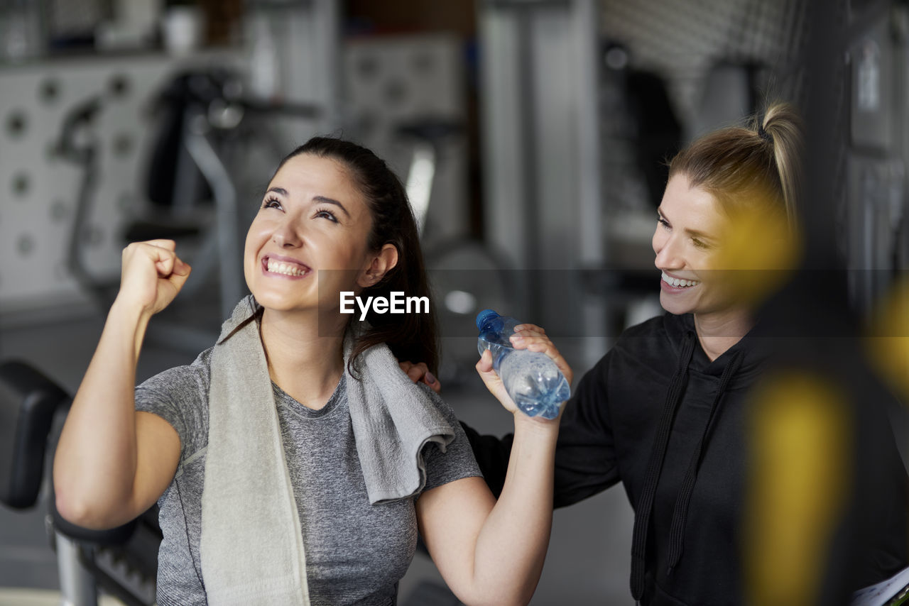 Trainer looking at cheerful woman in gym