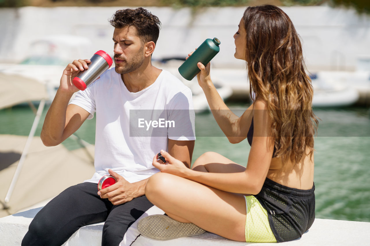 Couple drinking water while sitting outdoors