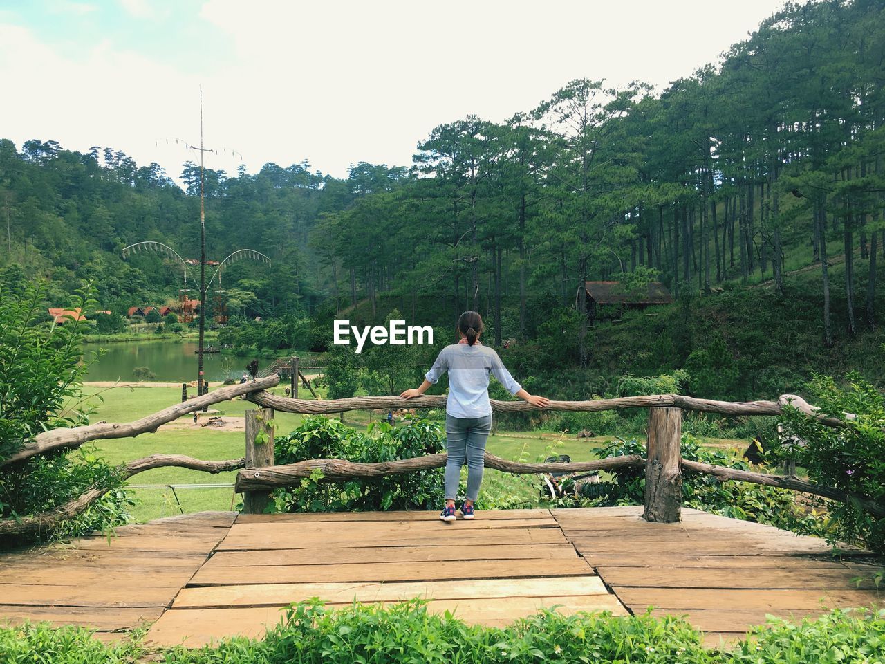 Rear view of woman standing on footbridge in public park