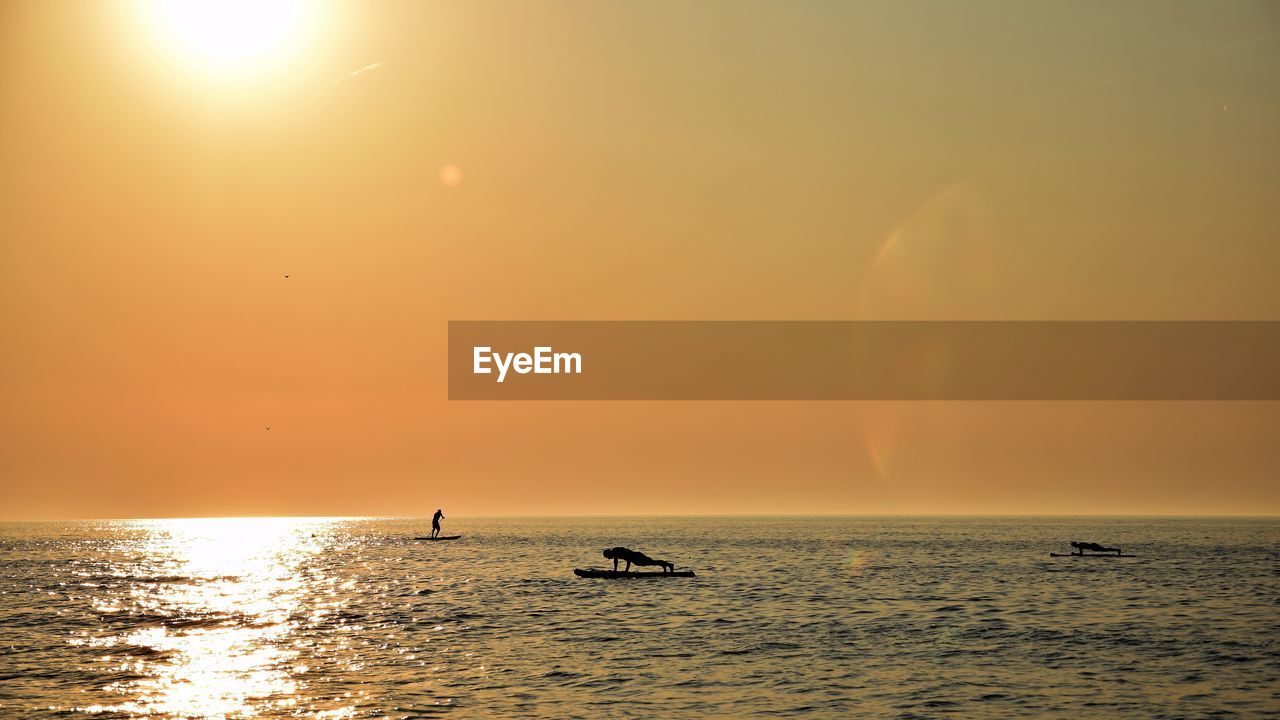 SILHOUETTE BOATS IN SEA AGAINST SKY DURING SUNSET