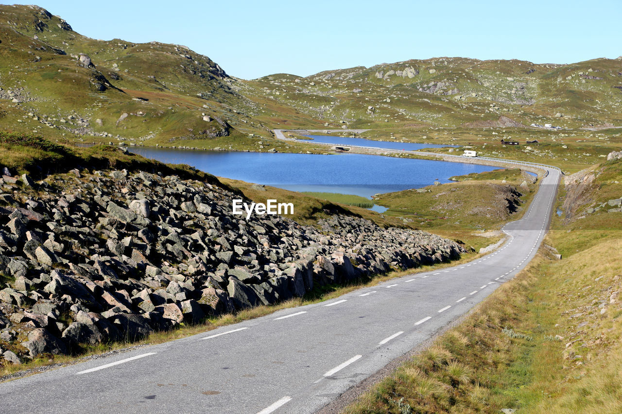 Scenic view of road by mountains against clear sky