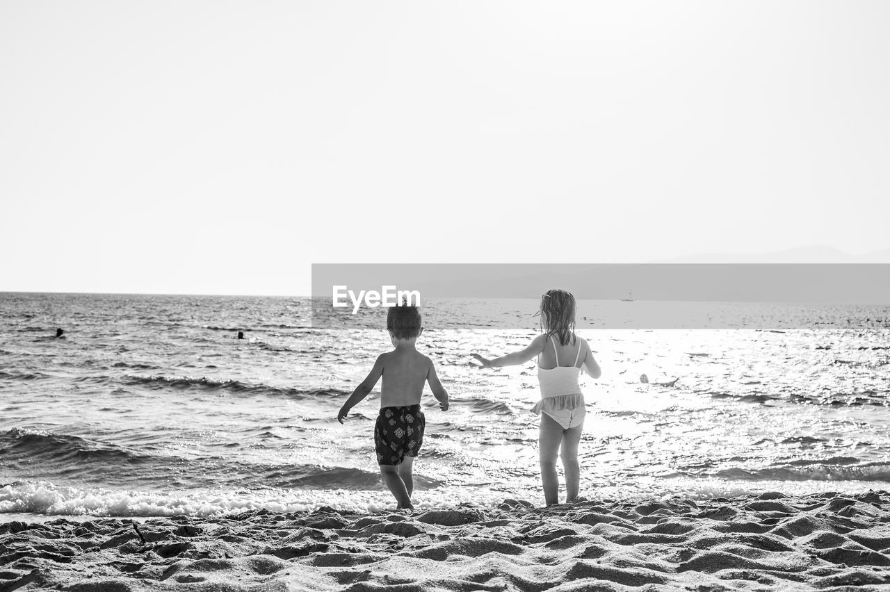 Two children, a boy and a girl, playing on the beach.