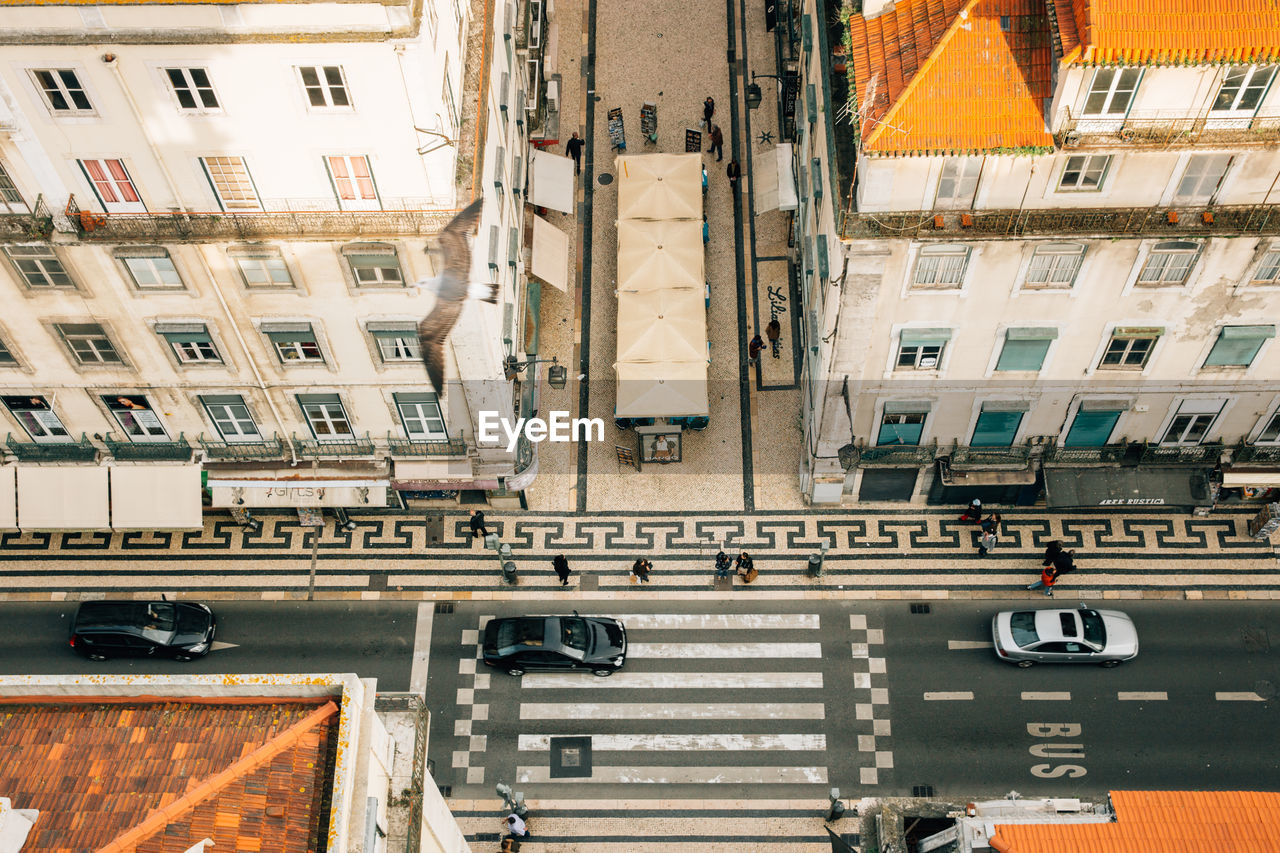 High angle view of people by cars on street amidst buildings