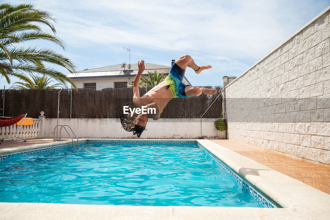 Man jumping in swimming pool against sky