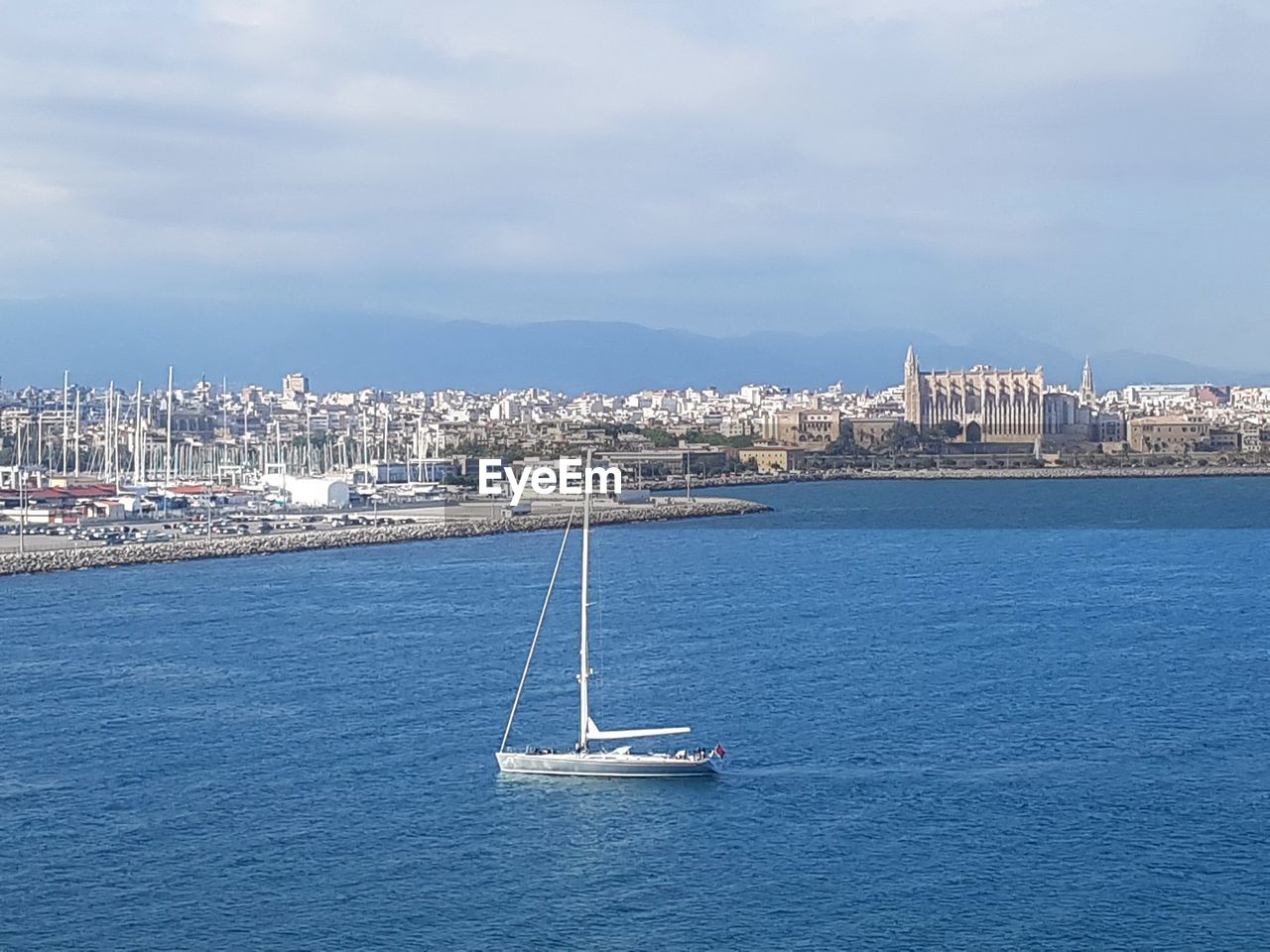 SAILBOATS IN SEA AGAINST CITYSCAPE