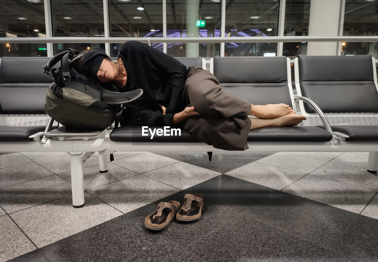 Woman sleeping on bench at airport