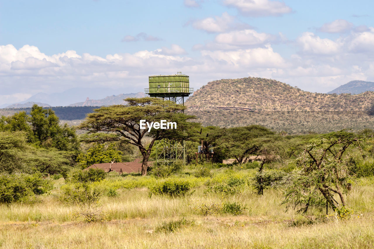A green water storage tank on stilts in the savannah of samburu park in kenya