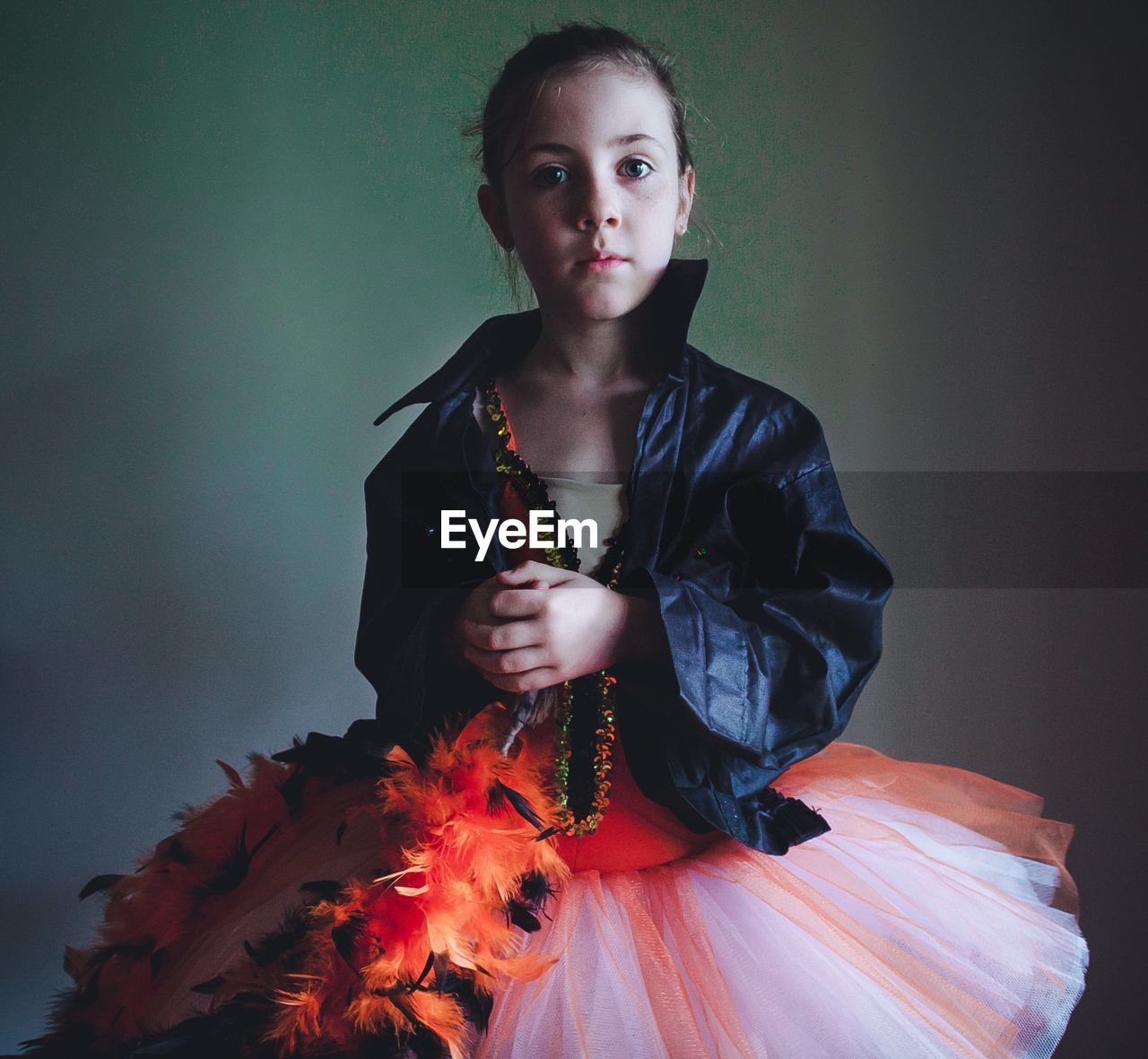 Portrait of confident girl wearing tutu and jacket against wall