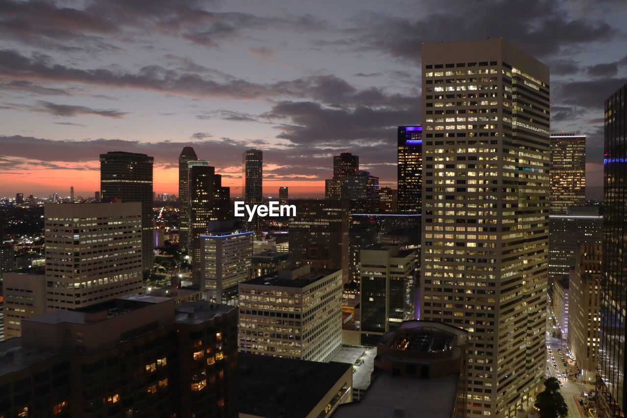 HIGH ANGLE VIEW OF ILLUMINATED CITY BUILDINGS AGAINST SKY