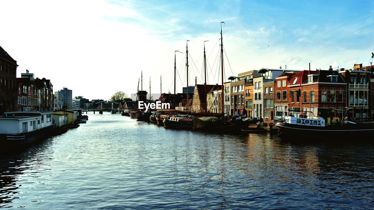 BOATS MOORED IN SEA BY CITYSCAPE AGAINST SKY