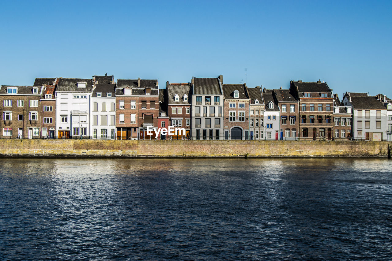 River by residential buildings against clear sky