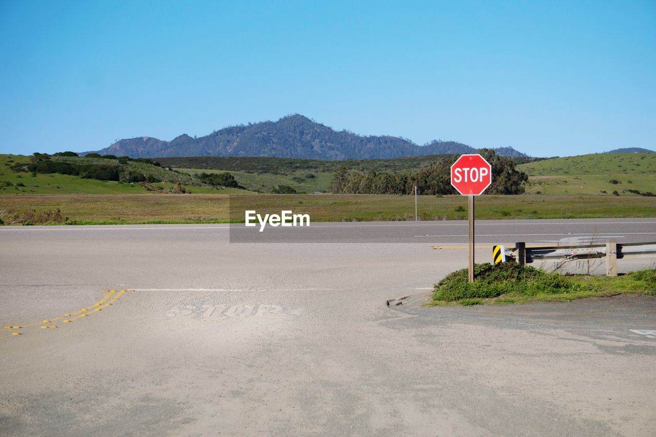 Road sign against clear sky and mountain view