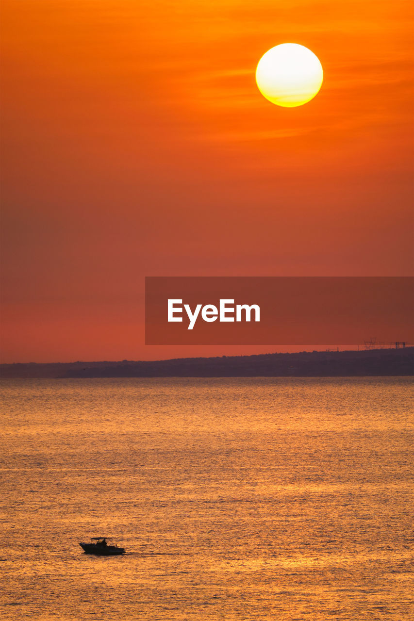 Small fishing boat in sea on sunset