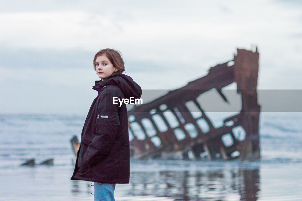 Portrait of girl standing at beach during sunset