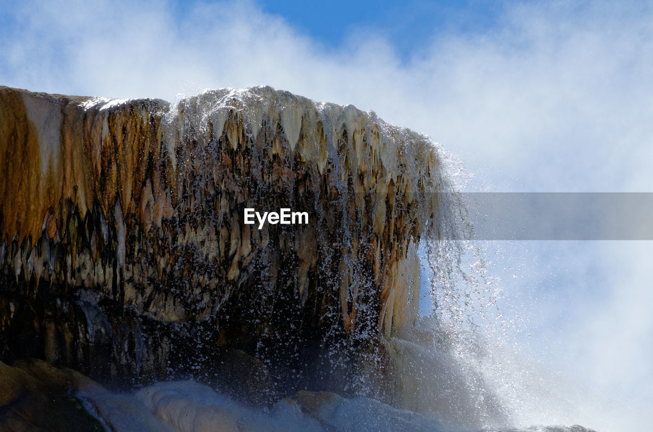 Low angle view of water falling from mountain against sky