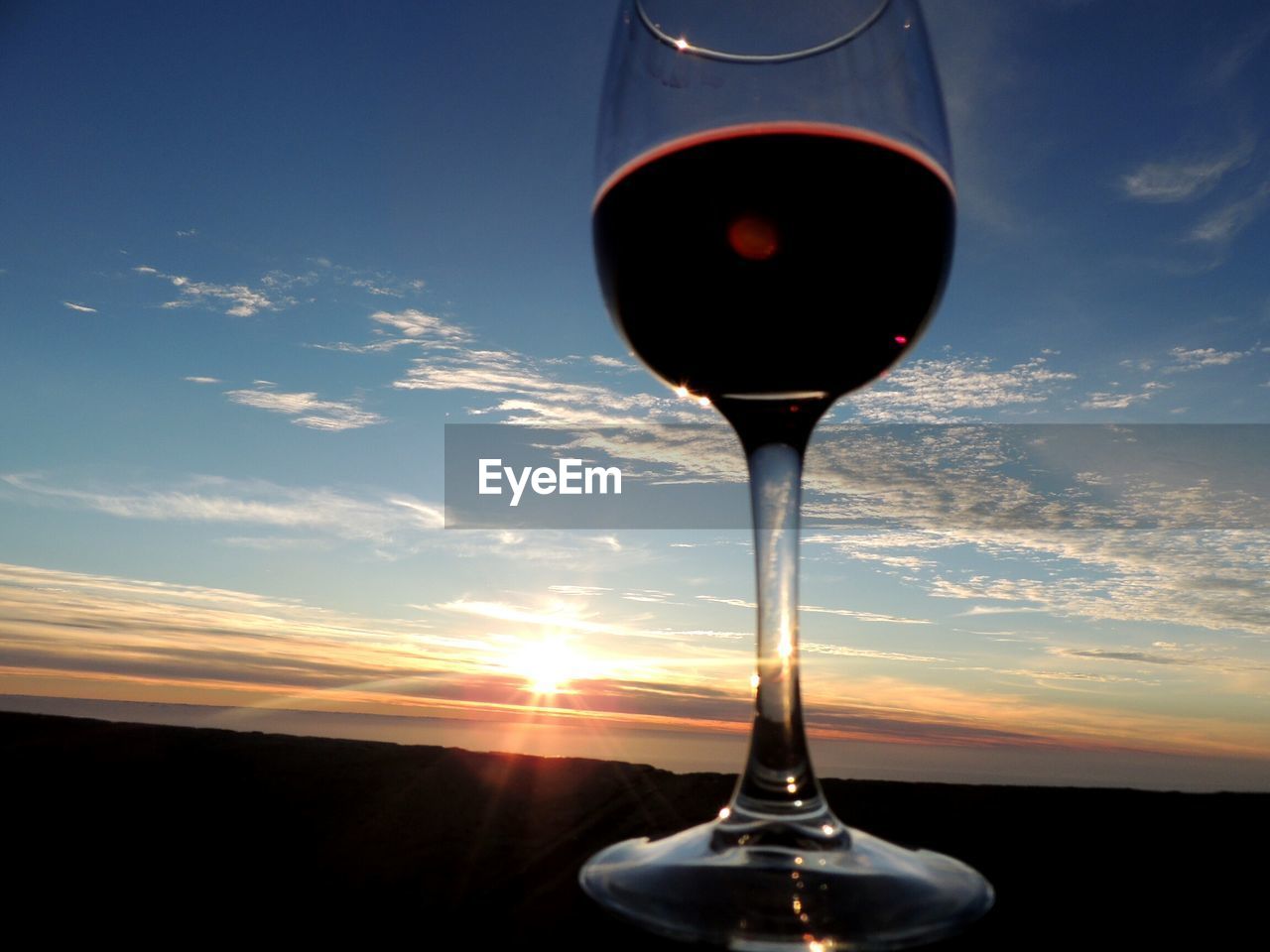 CLOSE-UP OF WINEGLASS AGAINST SKY