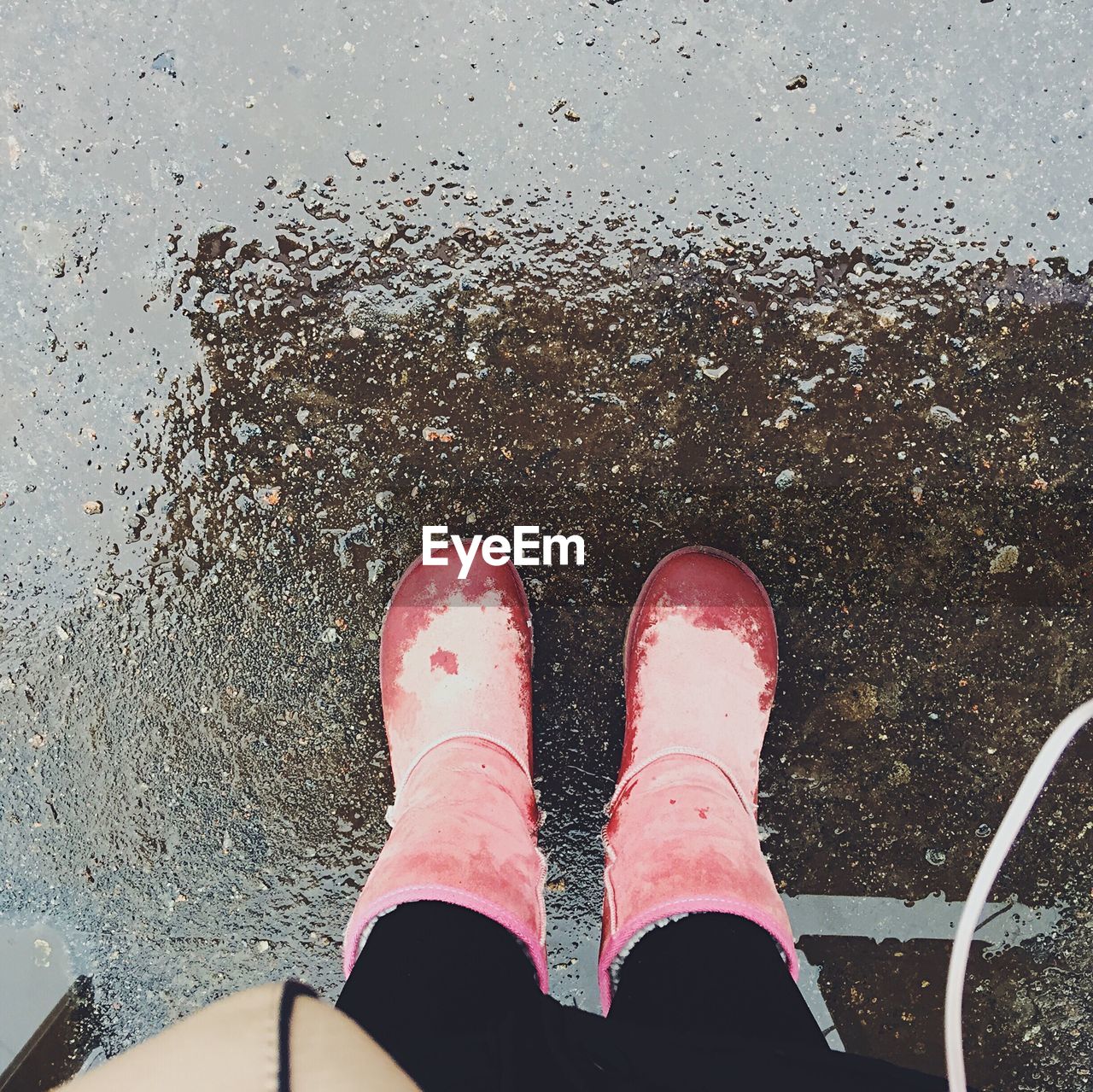 Low section of person wearing boots on wet street