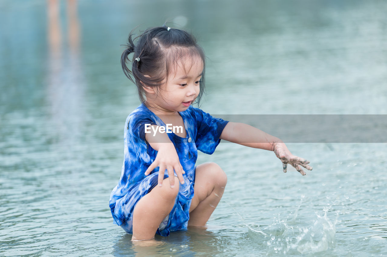 Cute girl crouching in sea