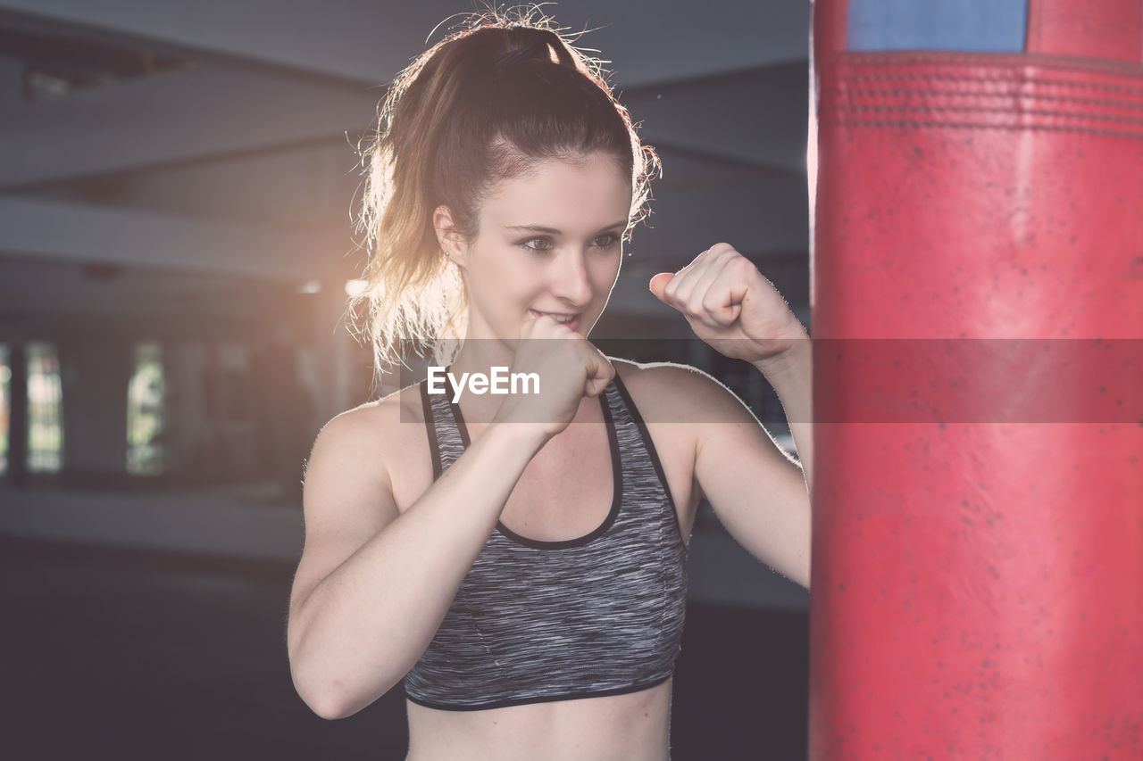 Female athlete training with punching bag in gym