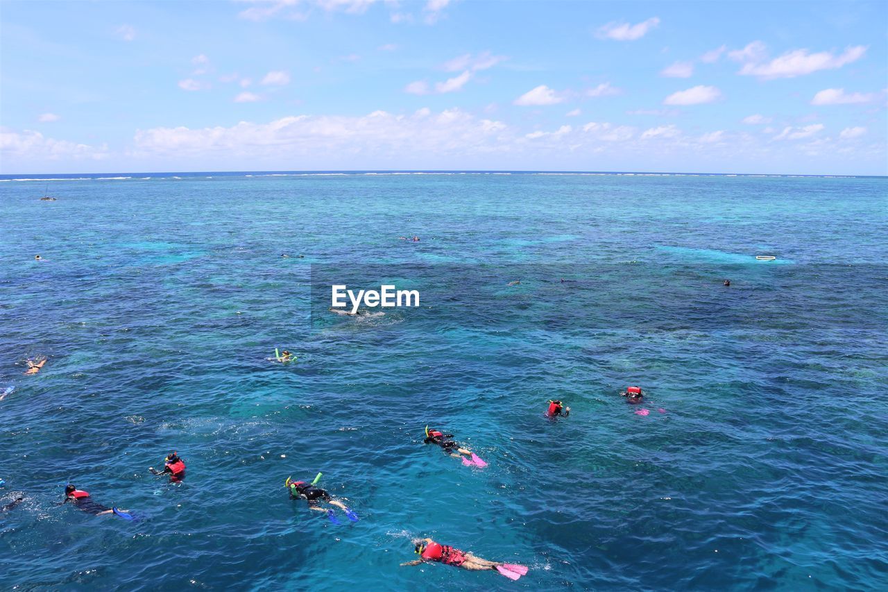 HIGH ANGLE VIEW OF PEOPLE IN SEA AGAINST SKY