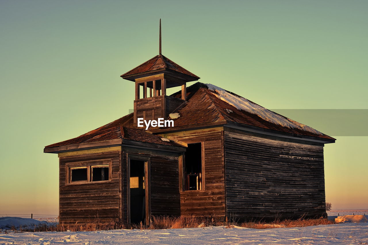 Exterior of house on field against clear sky during winter