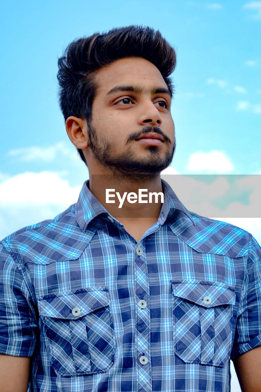 Young man looking away while standing outdoors