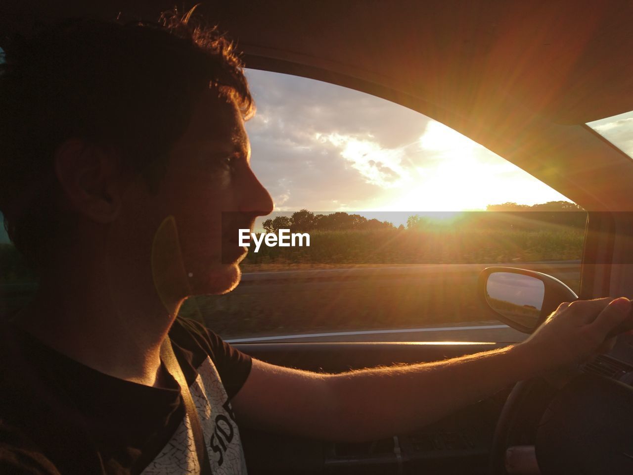 Close-up of man driving car during sunset