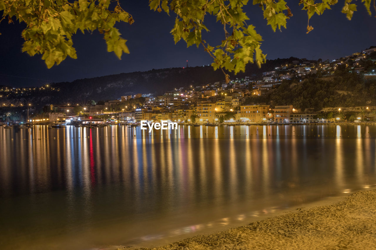 Scenic view of lake against illuminated city at night