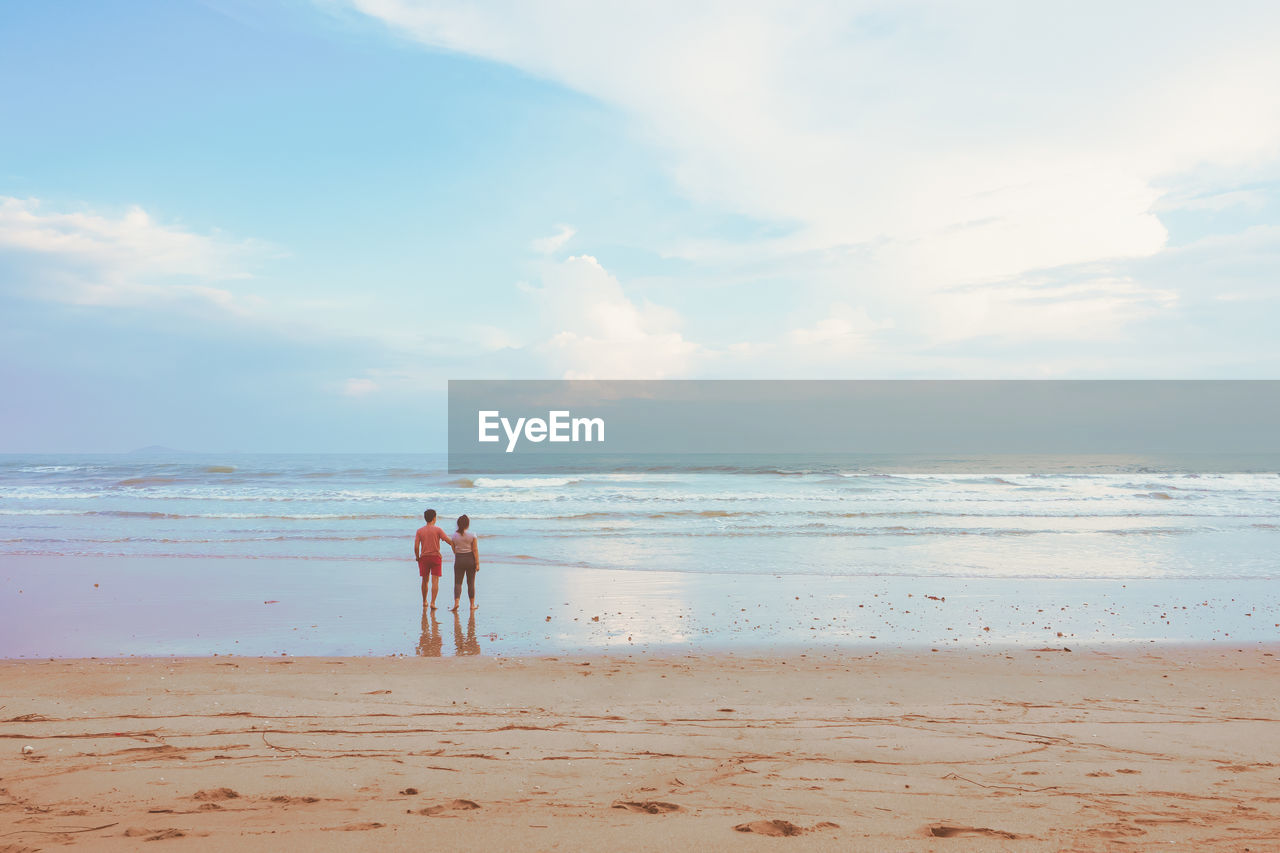 Happy romantic couple enjoying beautiful sunset walk on the beach. pastel colors tone