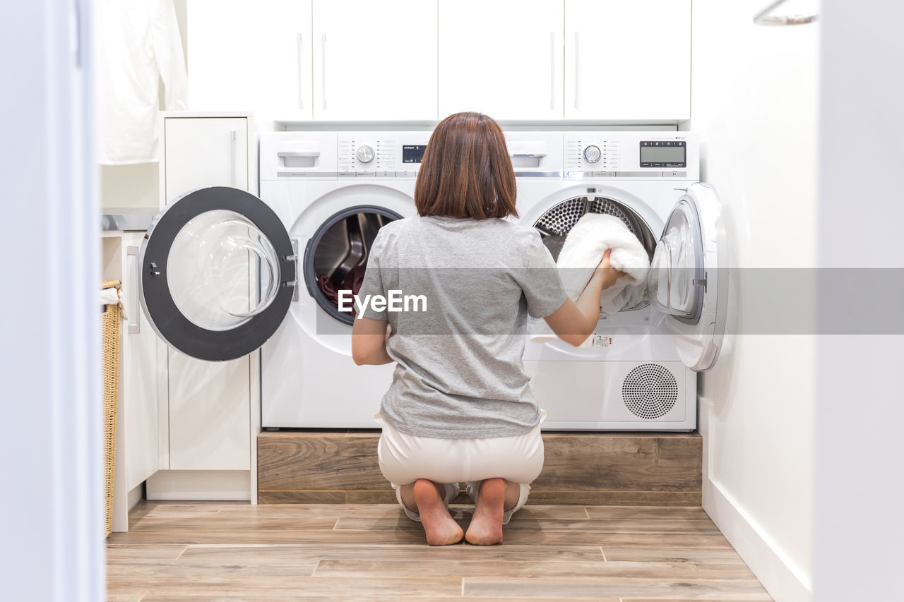 Rear view of woman removing clothes from washing machine